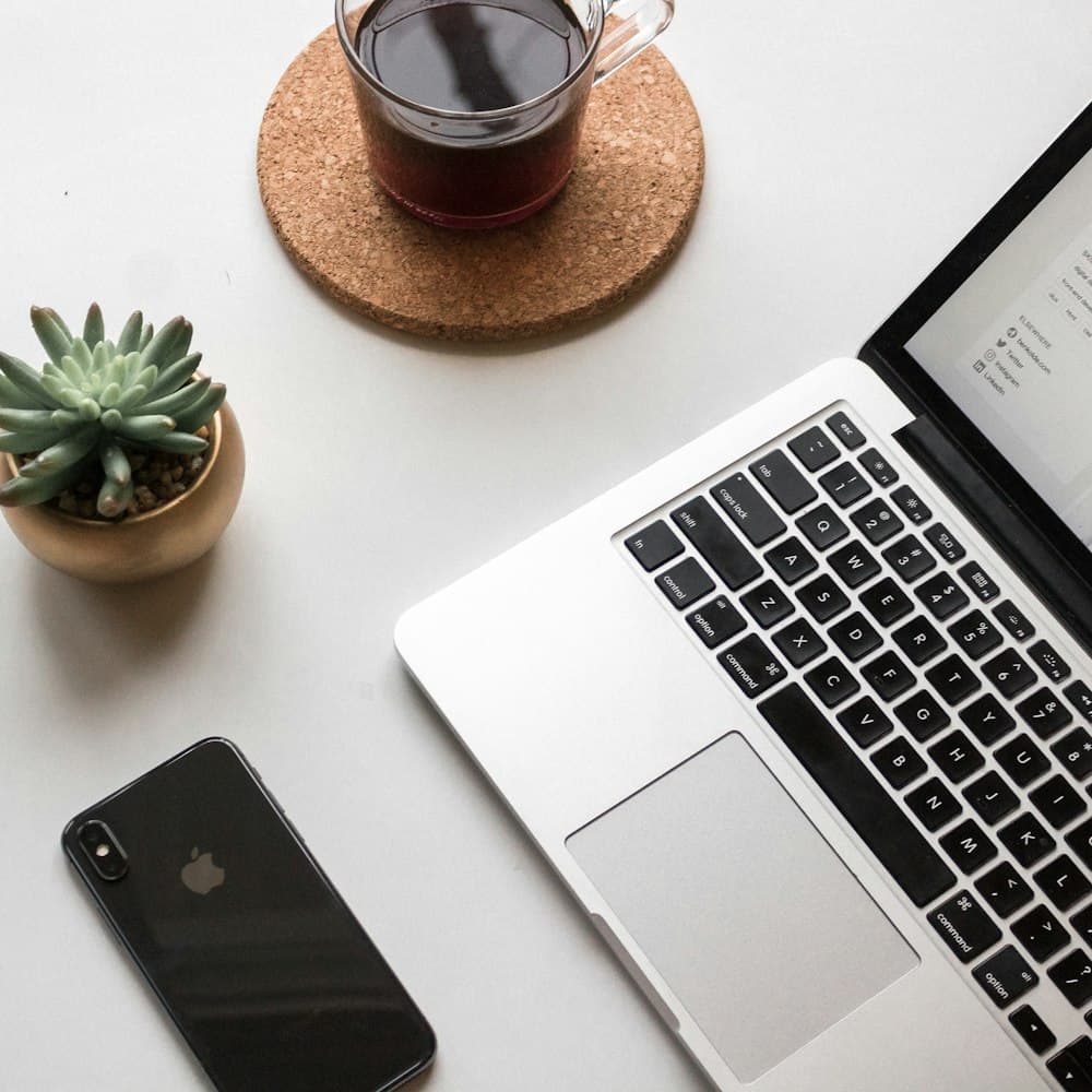 Minimal desk flat-lay with a laptop, phone, and coffee